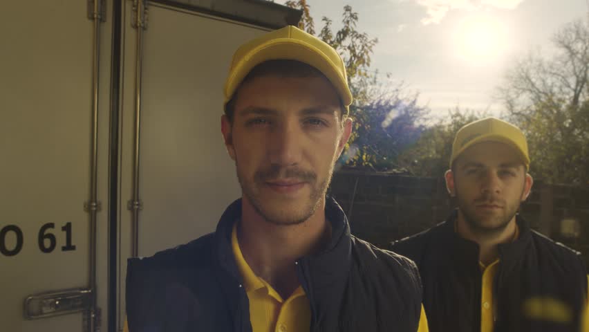 View from peephole , portrait of young courier or deliveryman standing in front of the door , ringing doorbell and waiting to give the delivery . Closeup face of logistic workers . Looking from eyelet