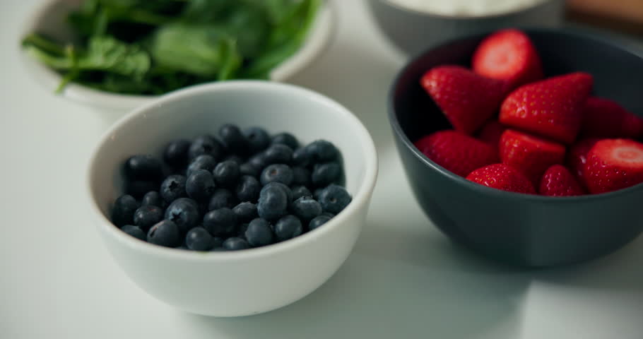 Fruit, bowls and nutrition with natural organic food or ingredients in kitchen for diet in home. Top view, strawberries or blueberries with mix recipe for health breakfast, vitamins or fiber in house