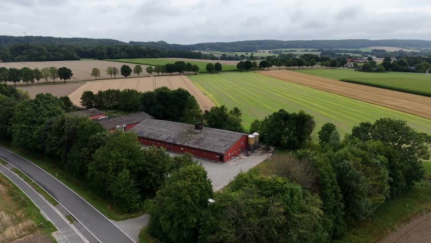 Traditional American farmstead building and barn in rural landscape. Cloudy summer day in Indiana. Aerial lateral wide shot. Rural road with forest trees. Quiet Suburb neighborhoods.