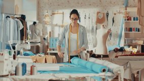 Beautiful Female Fashion Designer Adjusting Fabrics on a Tailored Mannequin. In Her Studio Various Sewing Items and Colorful Fabrics Laying around, Mannequins Standing, and Sketches Pinned. - Powered by Shutterstock - Get 15% off with code: PIKWIZARD15