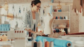 Beautiful Female Fashion Designer Adjusting Fabrics on a Tailored Mannequin. In Her Studio Various Sewing Items and Colorful Fabrics Laying around, Mannequins Standing, and Sketches Pinned. - Powered by Shutterstock - Get 15% off with code: PIKWIZARD15