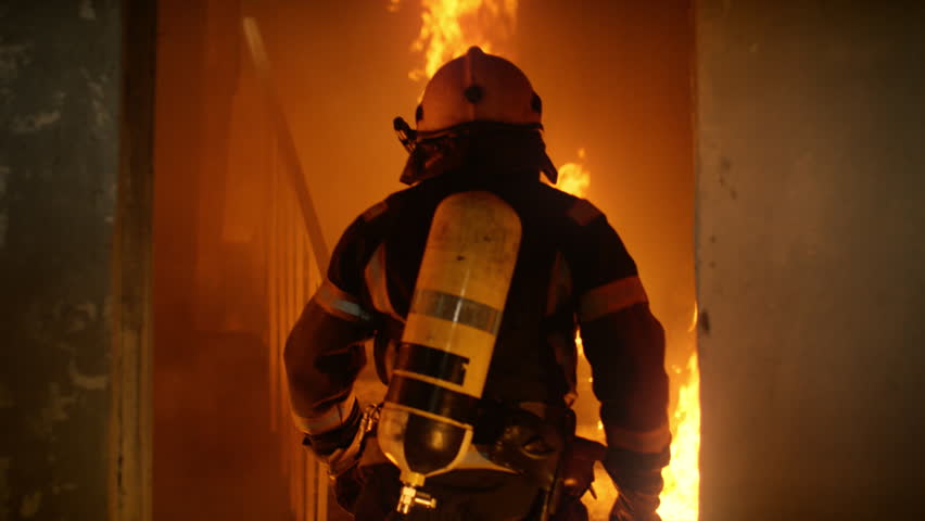 Two Firefighters in Full Protective Gear Run up a Smoky Staircase Inside a Burning Building, Surrounded by Intense Flames and Heavy Smoke, Moving Quickly to Reach People Trapped on the Upper Floor.