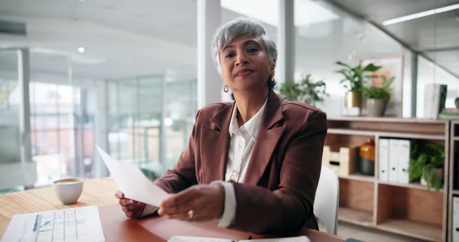 Documents, face and video call with business woman at desk in office for webinar or workshop. Paperwork, pov and wave with mature employee in workplace for greeting, introduction or virtual meeting