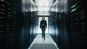Forward Shot: Engineer Walks Between Rows of Server Racks in Data Center. Advanced Network Hardware Cloud Computing, Artificial Intelligence, and Cyber Secure Business Operations. - Powered by Shutterstock - Get 15% off with code: PIKWIZARD15