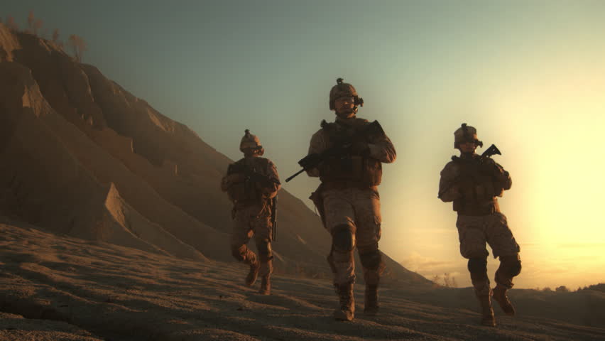 Three Soldiers in Uniform Walk Through a Desert Landscape at Sunset, Carrying Rifles. Professional Army ready to Fight Enemy. Portrait of Heroes Marching on a Dangerous Mission