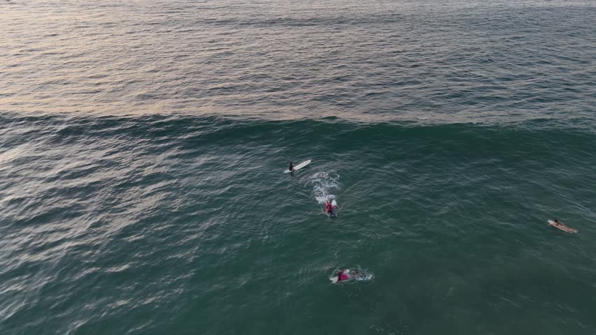 People surfing in the pacific ocean of costa rica while the sunset hour