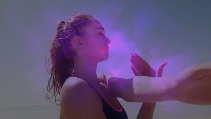 woman extending arm on beach initiating fitness demo with pink-purple energy haze pulsing forearm. Athletic, mindfulness, vitality, energy, serenity, modern, dynamic