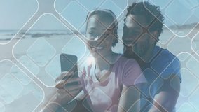 Pair sitting on beach using phone for selfie as grid overlay lens flare animating for technology. Romance, connection, digital, leisure, seaside, modern, intimacy - Powered by Shutterstock - Get 15% off with code: PIKWIZARD15