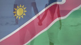 Namibian flag overlay fading in and settling as couple holding hands walking beach showcasing pride. Patriotism, unity, serenity, coastal, adventure, harmony, natural - Powered by Shutterstock - Get 15% off with code: PIKWIZARD15