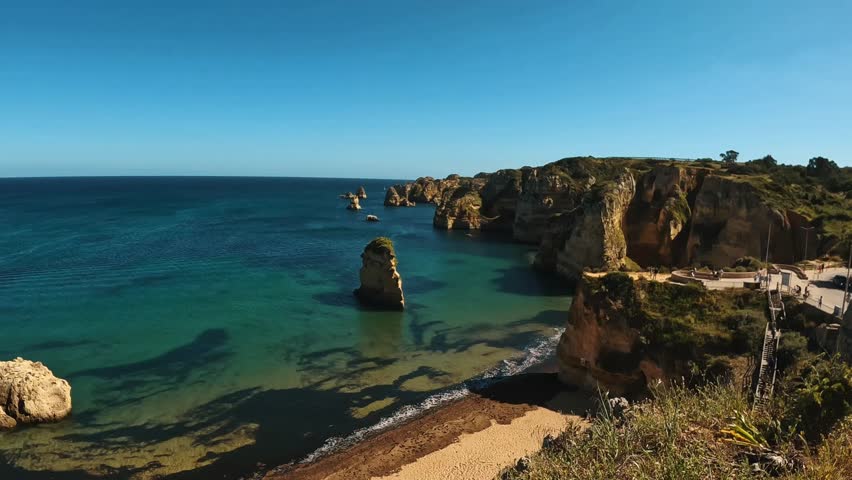 A clear sea with sandstone and limestone cliffs on the southern Algarve coast under a vivid sky in Portugal