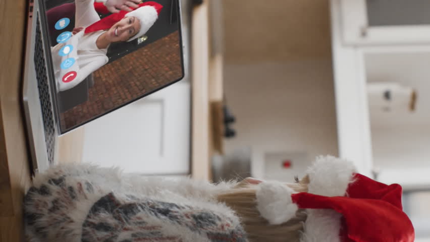 Green branches over woman wearing santa hat having a videocall on laptop during christmas. christmas celebration at home in quarantine during covid-19 pandemic concept