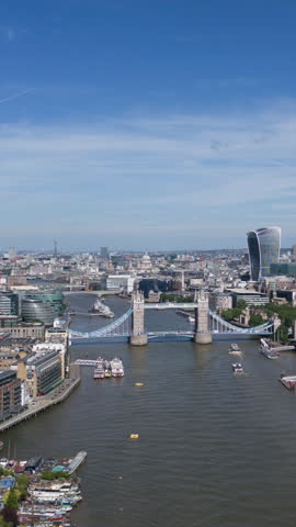 Vertical aerial hyperlapse of London skyline with boats going down the River Thames and cars going across Tower Bridge