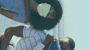 Animation of virus cells over african american family with face masks on sunny beach. healthy and active beach holiday concept digitally generated video. - Powered by Shutterstock - Get 15% off with code: PIKWIZARD15