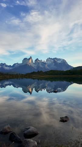 A vertical shot of Torres del Paine mountains reflecting on still water under a vivid sky in Patagonia Chile Magallanes Region