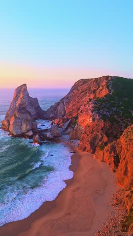 Ursa Beach, Sea Stacks, Cliffs and Atlantic Ocean Waves at Sunset. Portugal. Golden Hour. Aerial Drone View. Moving Forward Between Cliffs. Reveal Shot. Vertical Video