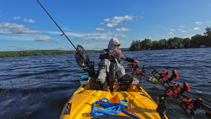 Man in sailing kayak pull anchor at lake after fishing, vacation or holiday outdoor. Water sport, after fishing tournament price. Man is sailing in kayak on lake at sunny day. Fishing game.
