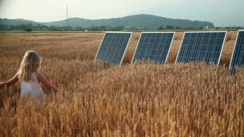 Little girl on a grain field with a solar power panels
