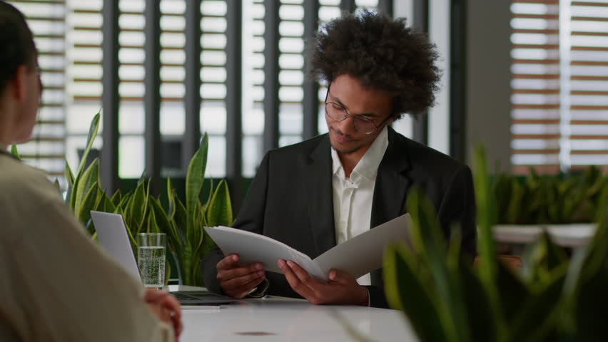 Two businessmen in business office African American leader insurance bank agent reading resume documents reject deny bad work result sad frustrated client man male worker holding head problem worried