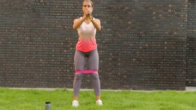 Outdoor Workout with Resistance Band, Woman Doing Squats in Activewear - Powered by Shutterstock - Get 15% off with code: PIKWIZARD15
