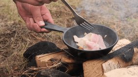 Chef cooking bacon in cast iron pan over campfire outdoors - Powered by Shutterstock - Get 15% off with code: PIKWIZARD15