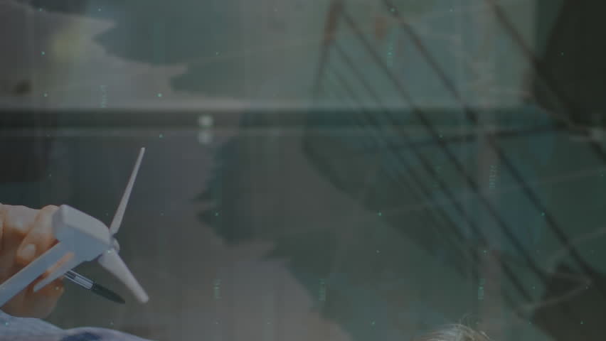 Animation of graphs, numbers over caucasian engineer inspecting windmill model and writing in book. Digital composite, multiple exposure, report, finance, growth, sustainable energy and technology.