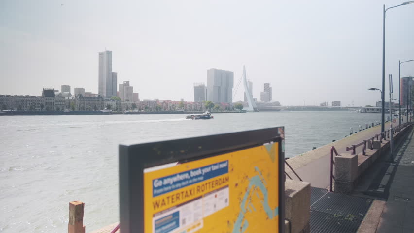 Erasmusbrug AKA The Swan during the day with skyscrapers, boats and a water taxi plan in Rotterdam, Netherlands, wide shot