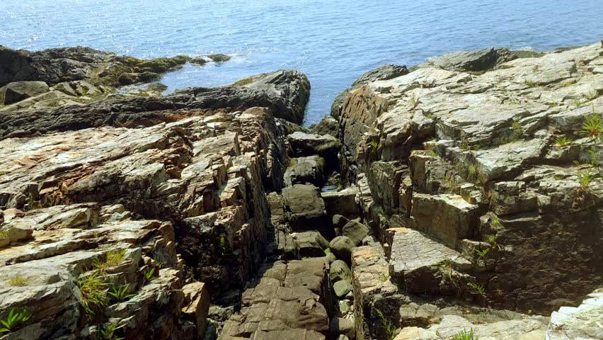 Granite rocks on ocean with a view of Ogunquit, Maine in the backgroud