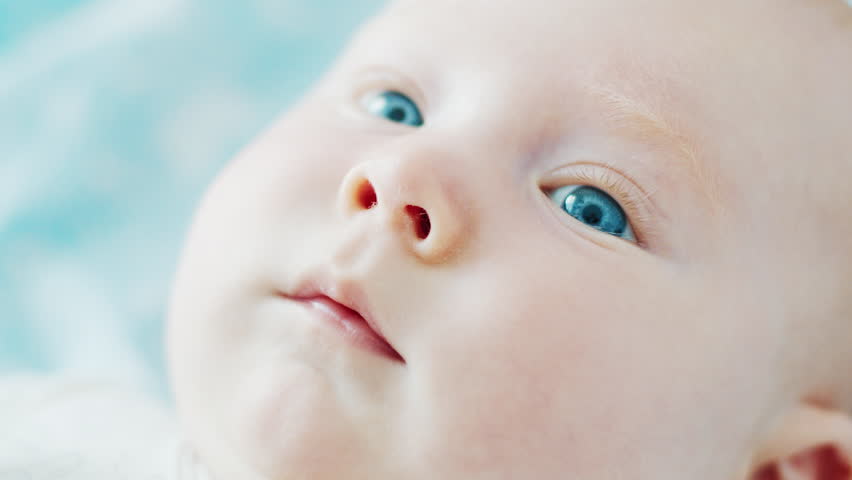 Close up portrait of the newborn boy (3 months old) with deep blue eyes in the bright white room
