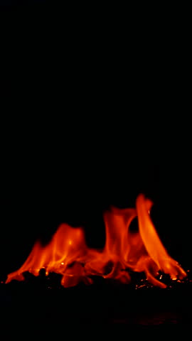 Vertical burning fire flame on ground isolated on black background, slow motion