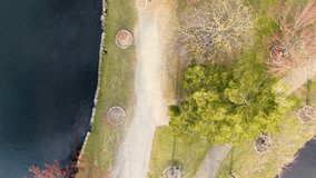 Aerial over man walking dog on Argyle Lake Park shoreline path tilts up to view Babylon, New York - Powered by Shutterstock - Get 15% off with code: PIKWIZARD15
