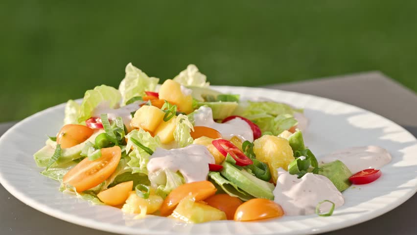 Chef put grilled shrimps on portion of freshly prepared healthy vegetable salad  on plate. outdoor cooking, food close-up