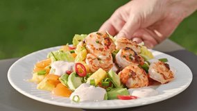 Chef put grilled shrimps on portion of freshly prepared healthy vegetable salad  on plate. outdoor cooking, food close-up - Powered by Shutterstock - Get 15% off with code: PIKWIZARD15
