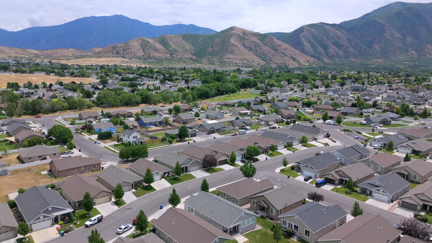 Stunning drone footage captures a serene Salt Lake City suburban community, showcasing an array of charming homes, spacious parks, and breathtaking mountain views. Utah, USA