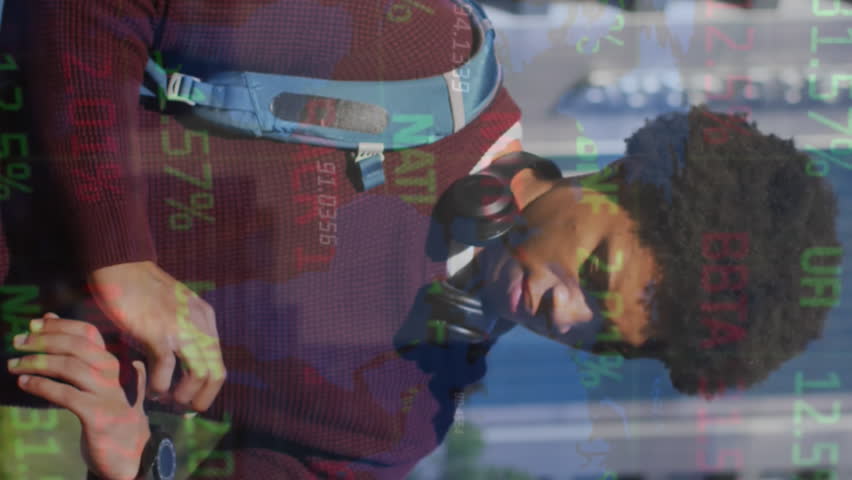 Animation of trading board and numbers over african american man standing and looking time on clock. Digital composite, multiple exposure, stock market, digits, abstract and technology concept.
