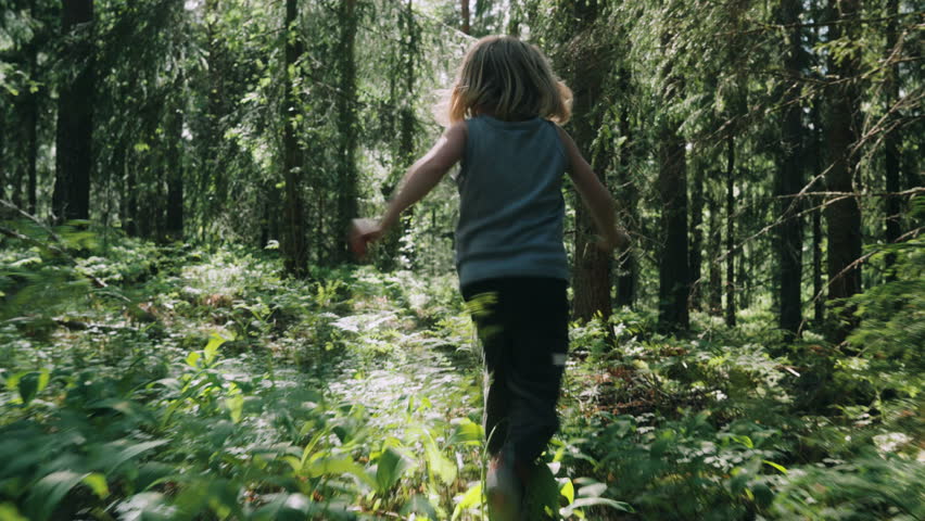 Wild child runs through remote woods as sun flits through trees, rear tracking