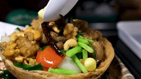 Cast iron skillet holding sizzling chicken cashew stir fry, garnished with cherry tomatoes, garlic, basil leaves, red chopsticks resting on rustic wooden surface - Powered by Shutterstock - Get 15% off with code: PIKWIZARD15