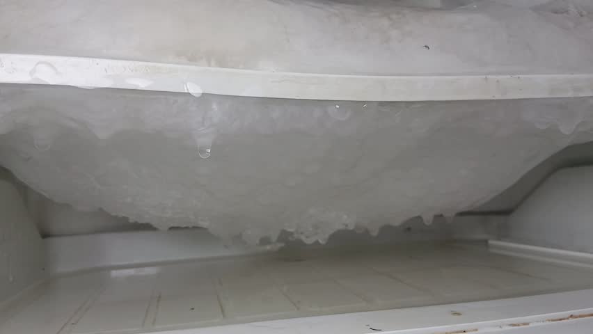 Freezer compartment with the door open. The freezer, covered in snow and ice, was opened to defrost