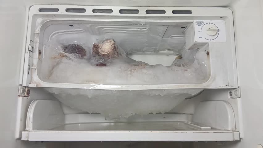 Freezer compartment with the door open. The freezer, covered in snow and ice, was opened to defrost