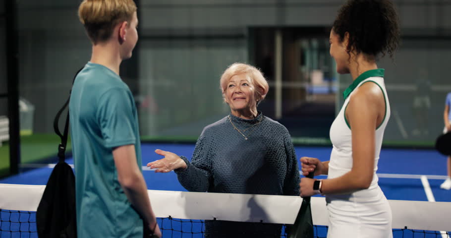 Grandmother, exercise and padel trainer with kid for training, development and family support. Woman, court and teen with coach for sports chat, fitness lesson and introduction in tennis club