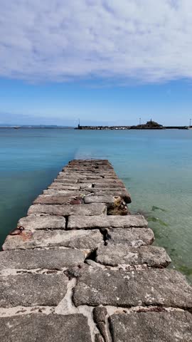 Tranquil scene of colorful fishing boats moored in palmeira harbor, with a rocky islet and a statue in the background, under a clear blue sky in a coruña, spain