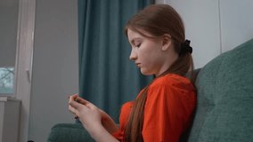 Teenage girl relaxing on comfortable home sofa, smartphone in hand, browsing social media or playing mobile game with casual, carefree demeanor - Powered by Shutterstock - Get 15% off with code: PIKWIZARD15