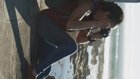 Social media notifications animation over woman sitting by ocean taking photos. Technology, photography, digital, vacation, lifestyle, travel - Powered by Shutterstock - Get 15% off with code: PIKWIZARD15