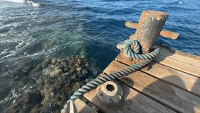 Turquoise water gently laps against a wooden pier with a rusty bollard and a mooring rope - Powered by Shutterstock - Get 15% off with code: PIKWIZARD15