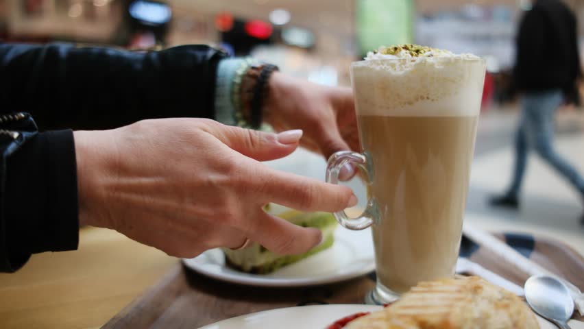 Girl Takes A Glass Of Fresh Aromatic Latte Coffee In A Cafe In The Trade Center