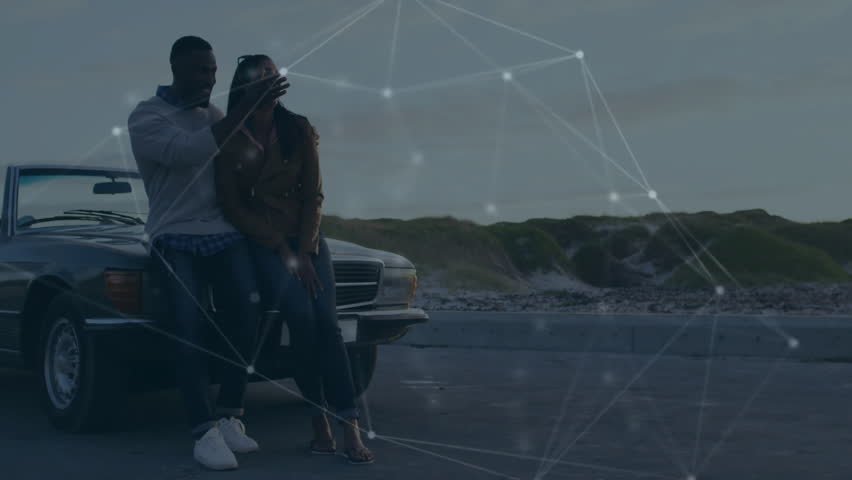 couple arriving coast overlook for travel ad, leaning on car hood brushing hair and pointing dunes. Romantic, coastline, sunset, leisure, adventure, scenic, outdoor