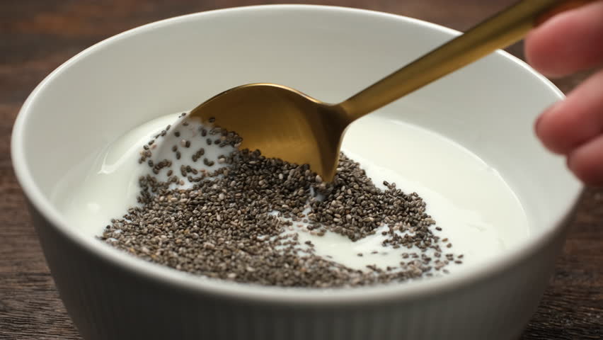Stirring dry chia seeds with cream yogurt. Cooking Chia pudding healthy snack