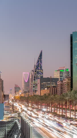 Aerial day to night timelapse of King Fahd Road in Riyadh, Saudi Arabia. Bustling traffic with cars and taxis near the illuminated Riyadh National Library, surrounded by modern towers and skyscrapers