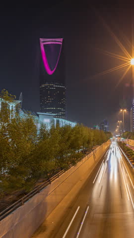 Panoramic aerial night timelapse of Riyadh featuring highway tunnel traffic, Kingdom Tower the tallest skyscraper and landmark of Saudi Arabia's capital. Illuminated modern buildings surround scene