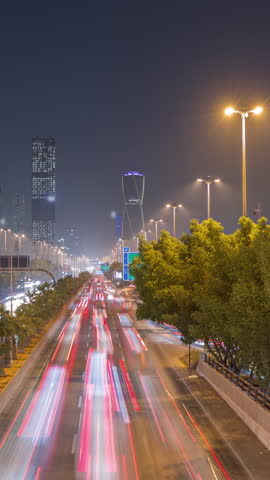 Aerial timelapse view of busy highway traffic on King Fahd Road with the iconic twisting skyscraper in Riyadh, Saudi Arabia. Illuminated streets and trees. Eighth-tallest twisting tower in the world.