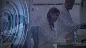 Indian woman scientist tapping tablet while round interface animating code for lab data analysis. Scientists, laboratory, technology, innovation, data, collaboration, research - Powered by Shutterstock - Get 15% off with code: PIKWIZARD15